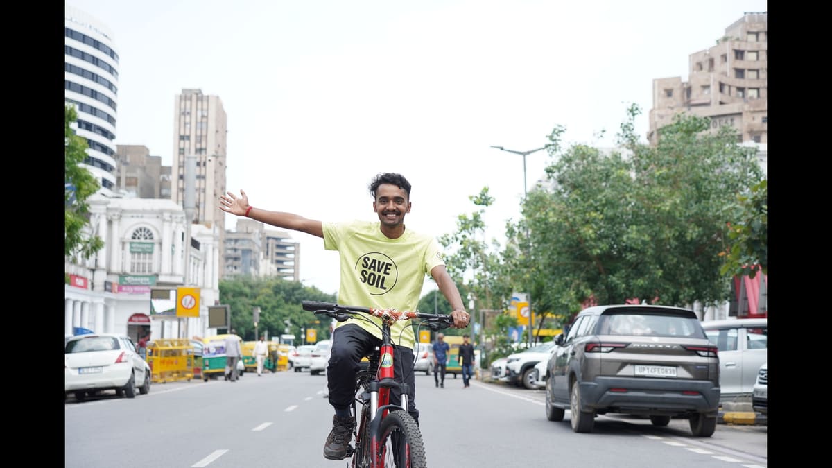 Sahil Jha riding his bicycle with arms outstretched on a street in Delhi